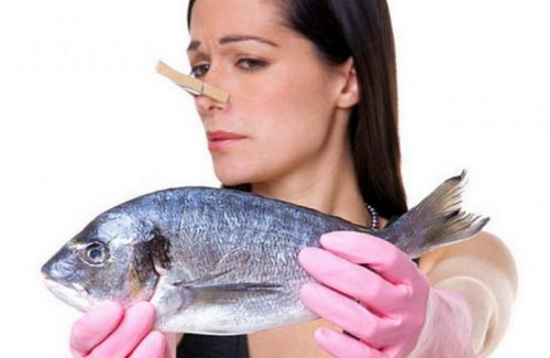 Женщина держит в руках пахнущую рыбу